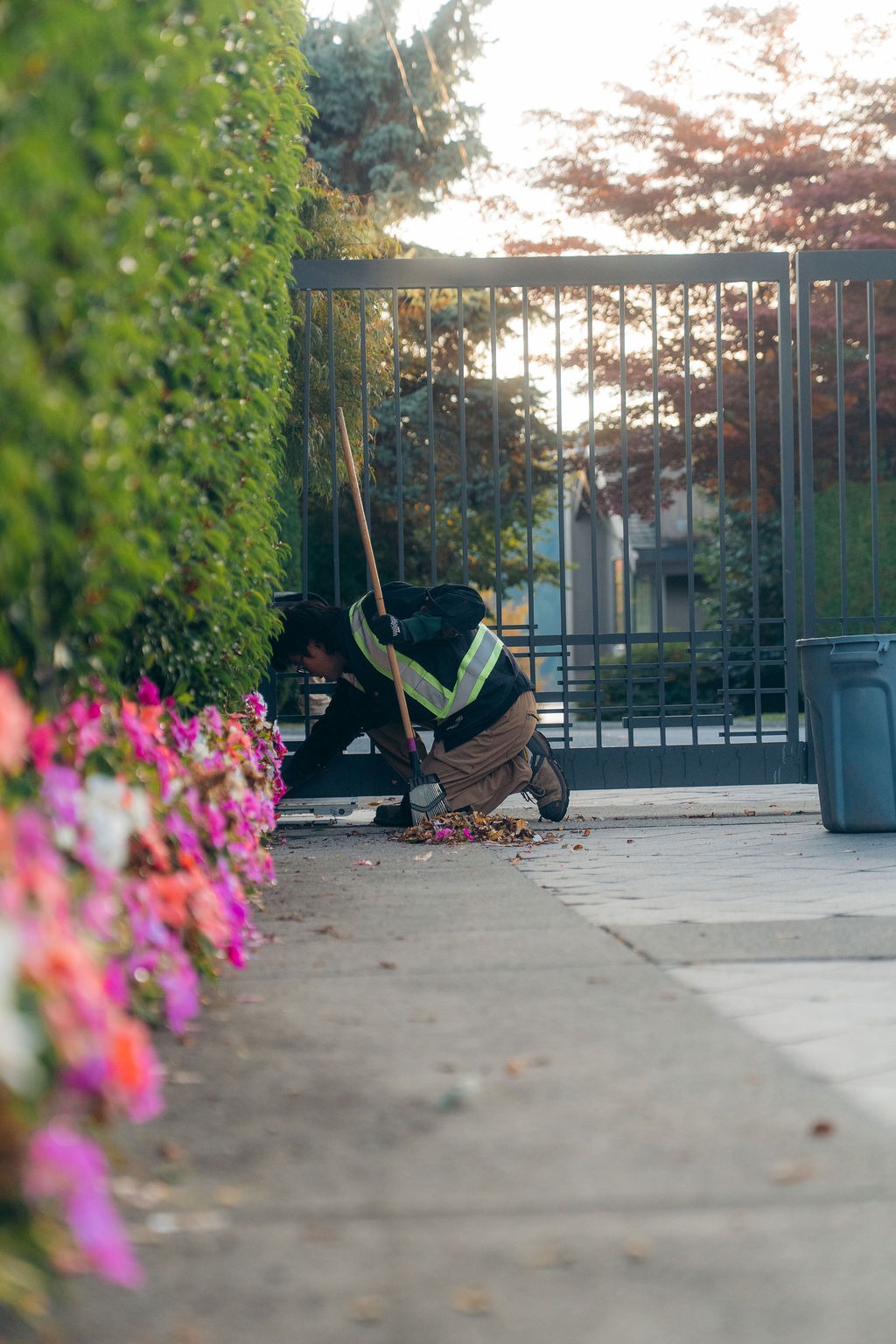Groundskeeper sweeping leaves beside garden gate