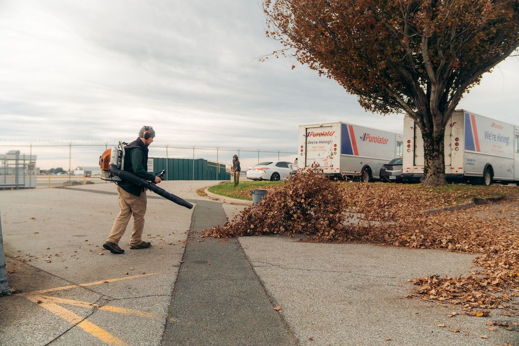 Worker using leaf blower in parking lot