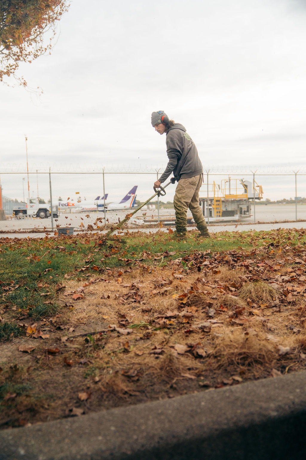 Groundskeeper trimming grass near airport runway