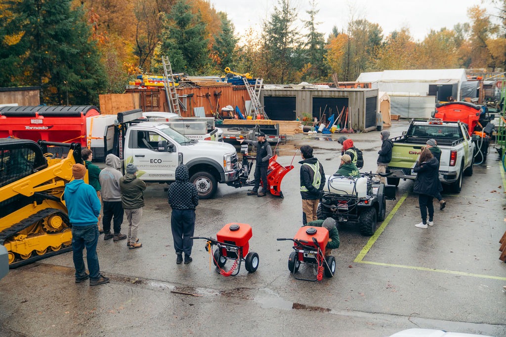 Landscaping crew gathered around truck with snow plow