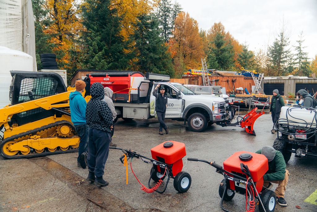Workers inspecting snow removal equipment in yard
