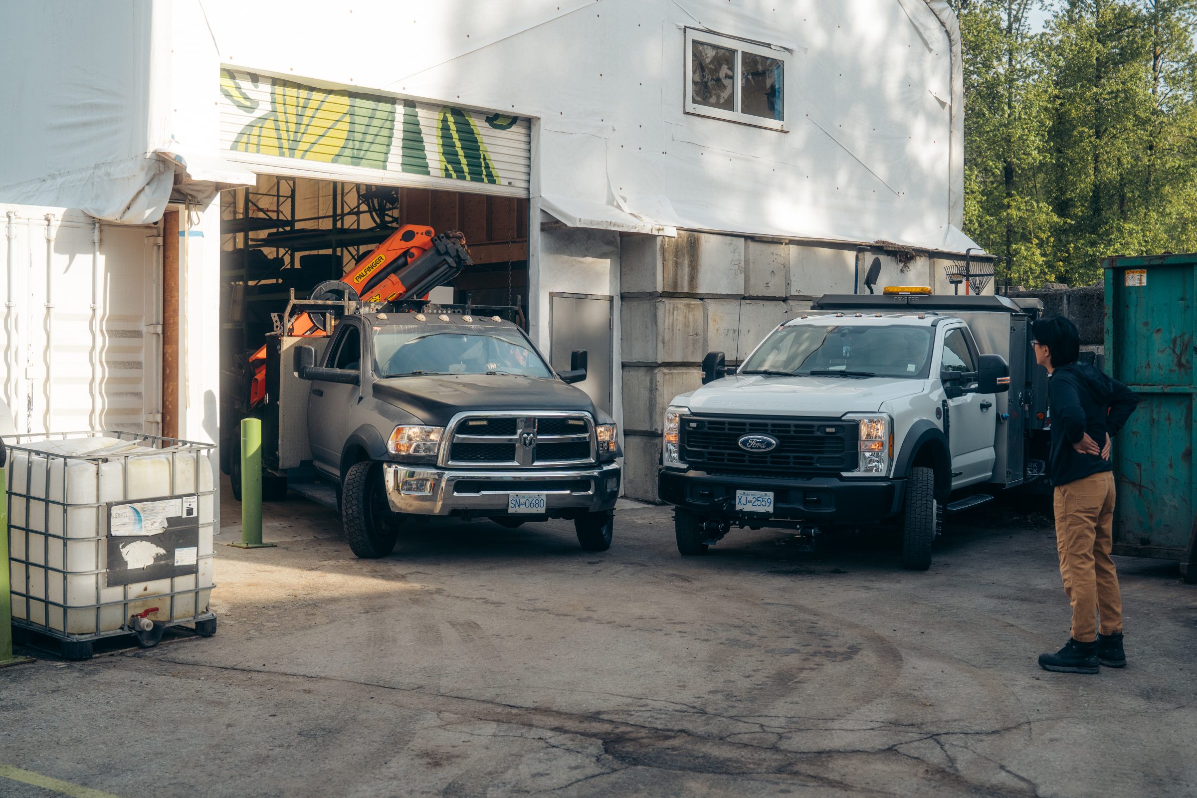 Two pickup trucks parked outside industrial warehouse