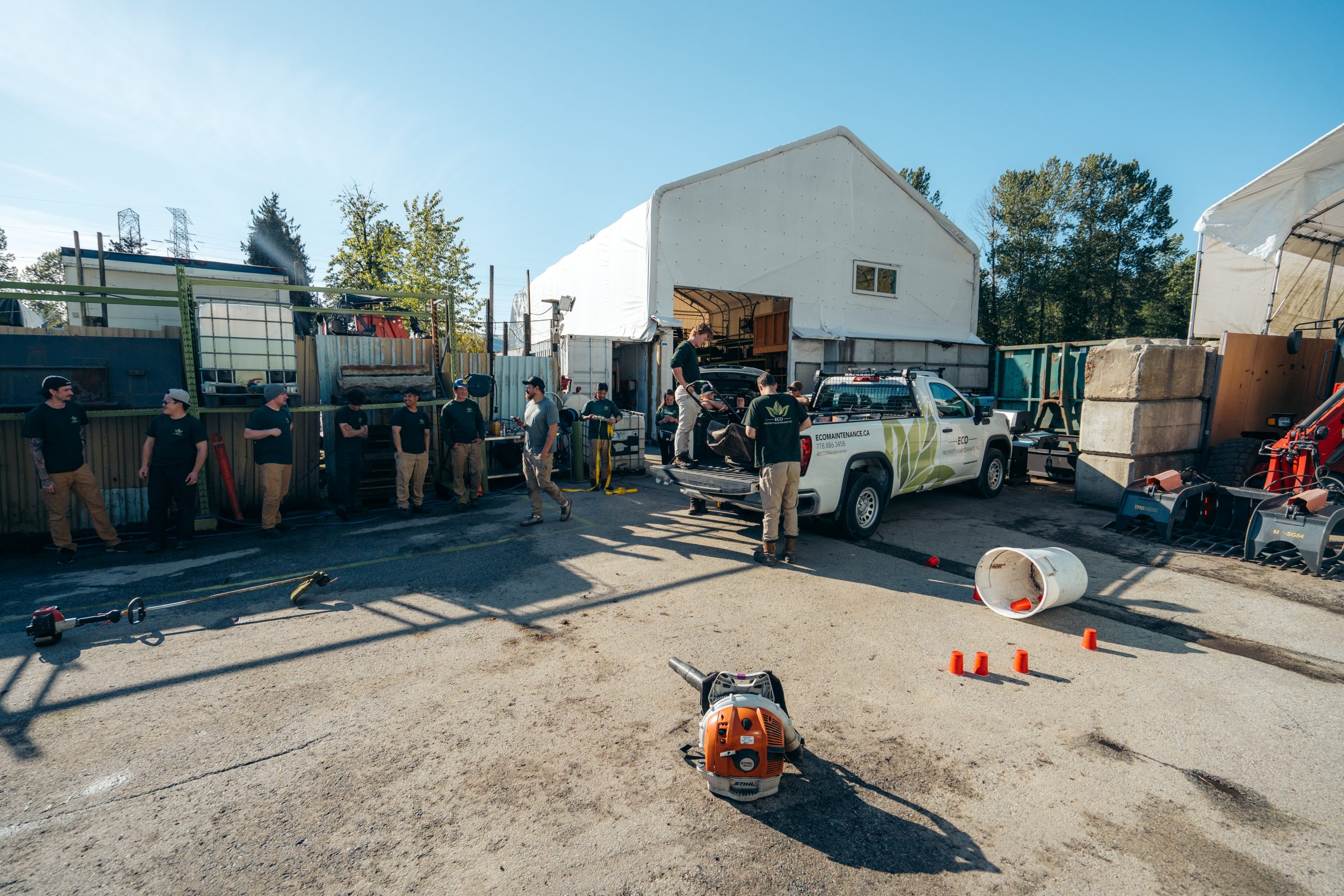 Landscaping crew preparing equipment beside white work truck
