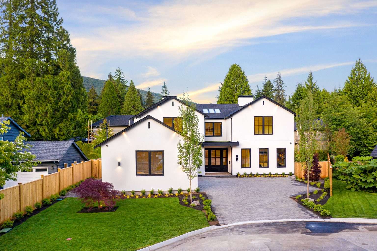Modern white two-story home with landscaped yard