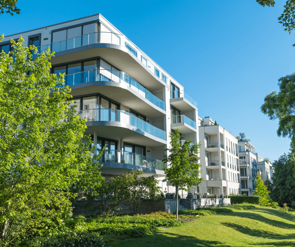 A row of apartment buildings with their garden area and side walk.