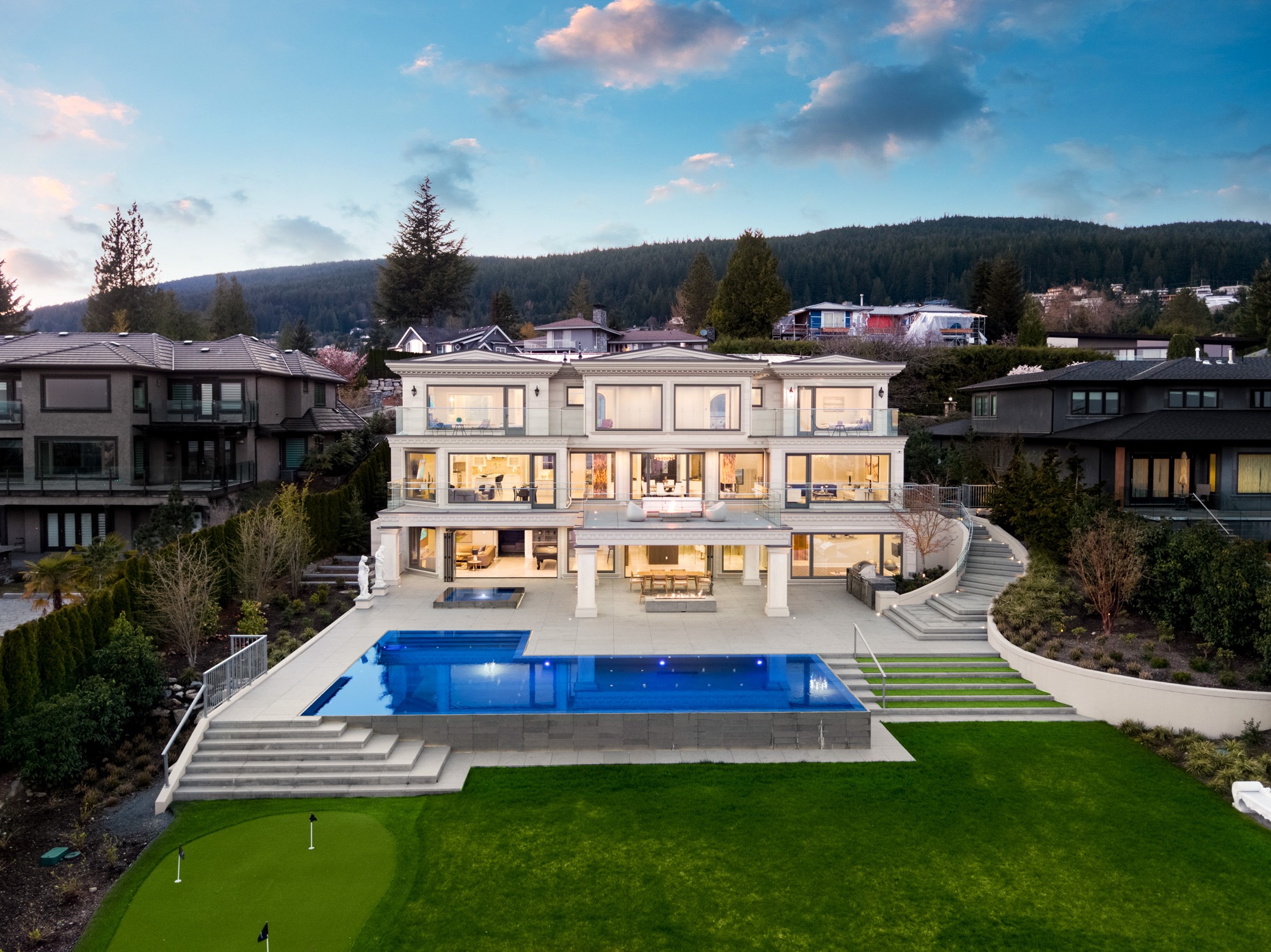 Luxury hillside mansion with infinity pool at dusk