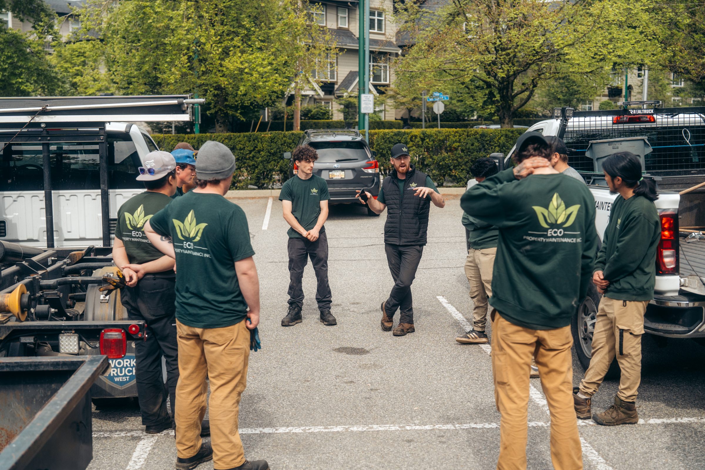Landscaping crew meeting in parking lot with trucks