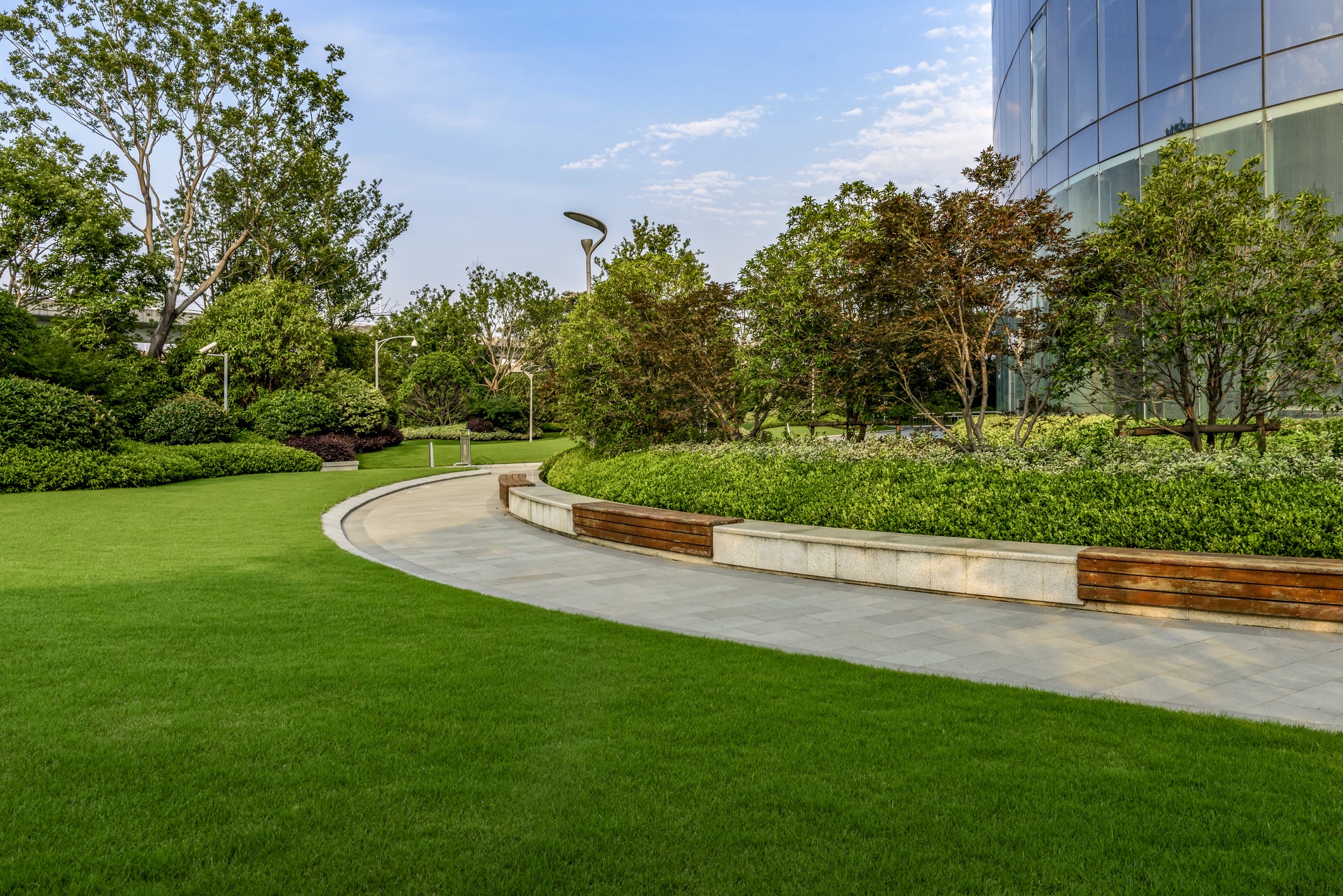 Curved walkway in landscaped garden by glass building
