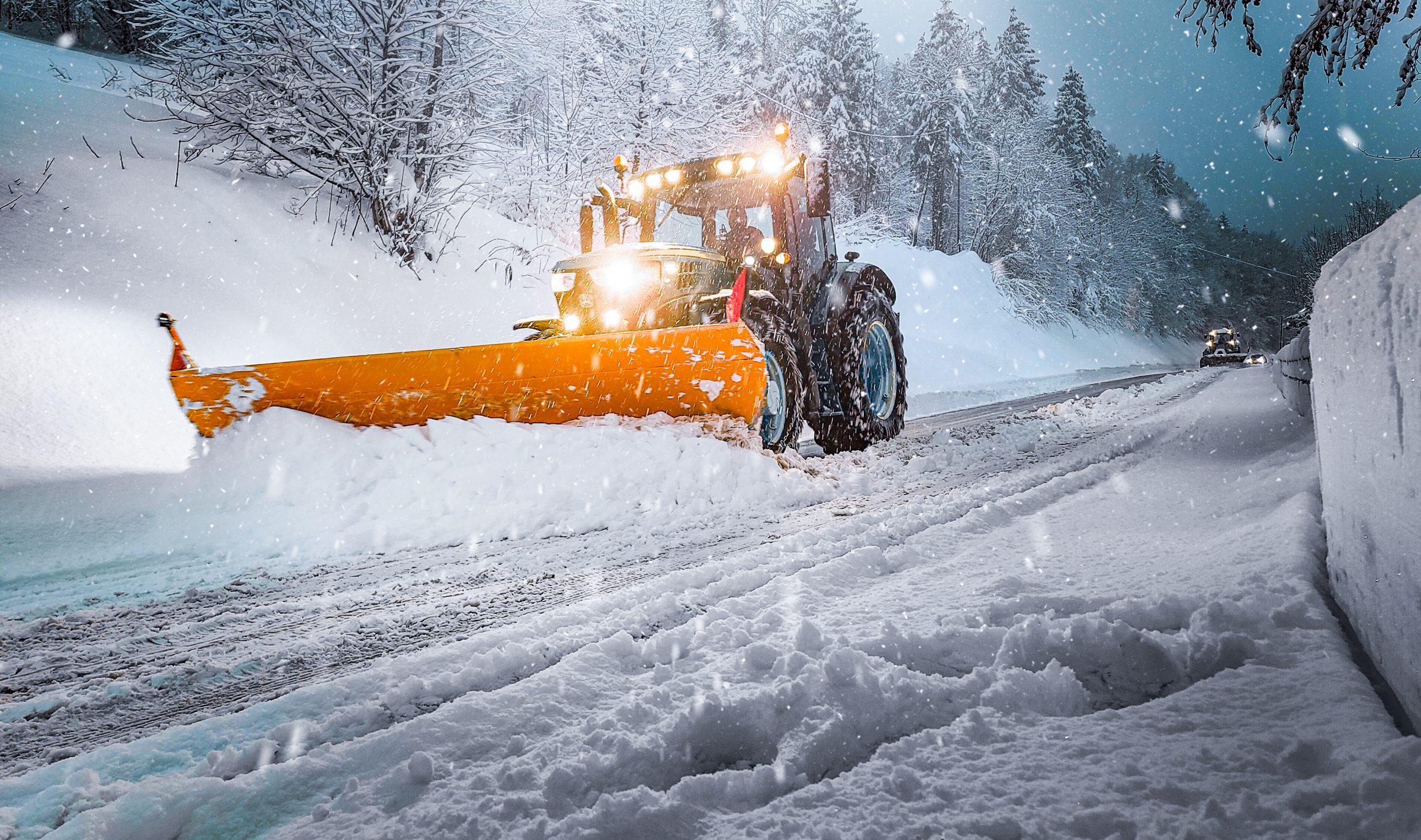 Tractor snowplow clearing snowy forest road
